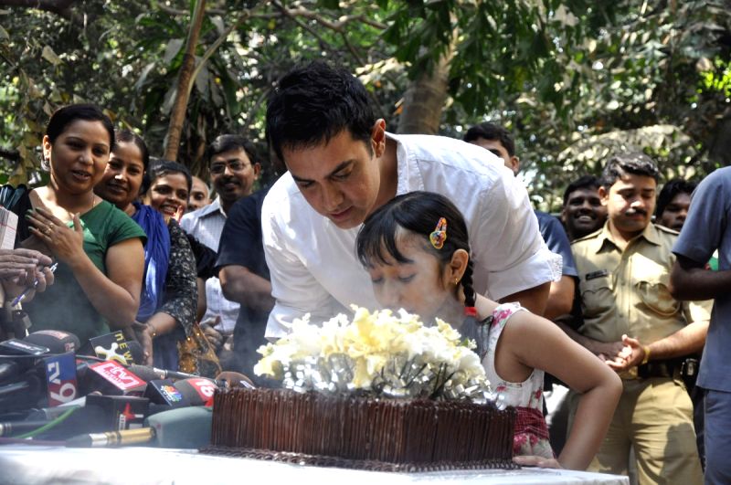 Aamir KHan blows his 45rd birthday candles with one of his child fans as he celebrated his birthday with media today at his home in Mumbai.