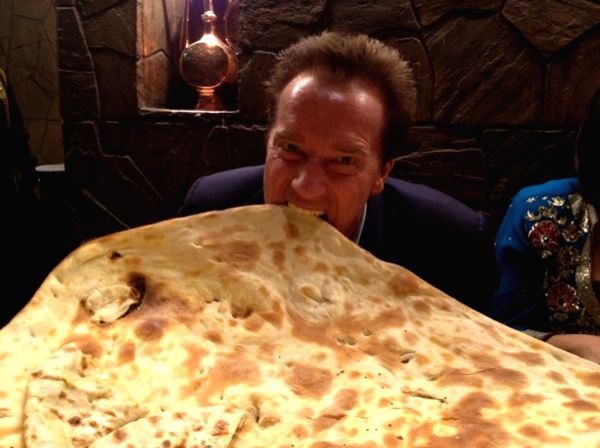 Arnold Schwarzenegger eating a huge naan especially created for him