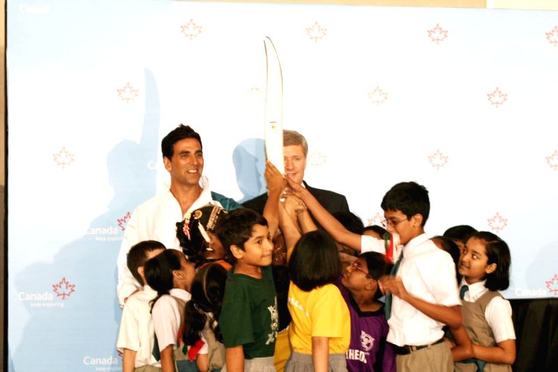Canadian Prime Minister Stephen Harper and Bollywood Actor Akshay Kumar pose with a jacket, which will be worn by torchbearers for the 2010 Winter Olympics torch relay during an event at Trident in Mumbai on Monday, 16 November 2009.