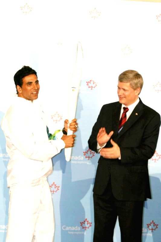 Canadian Prime Minister Stephen Harper and Bollywood Actor Akshay Kumar pose with a jacket, which will be worn by torchbearers for the 2010 Winter Olympics torch relay during an event at Trident in Mumbai on Monday, 16 November 2009.