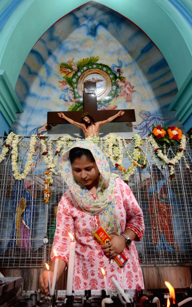 A Christian woman devotee lights a candle to observe Good Friday