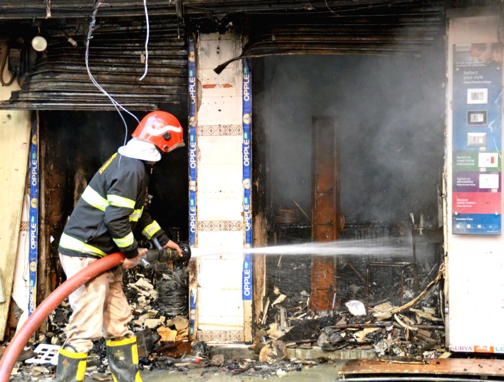 A firefighter attempts to douse fire after it broke out in the shops