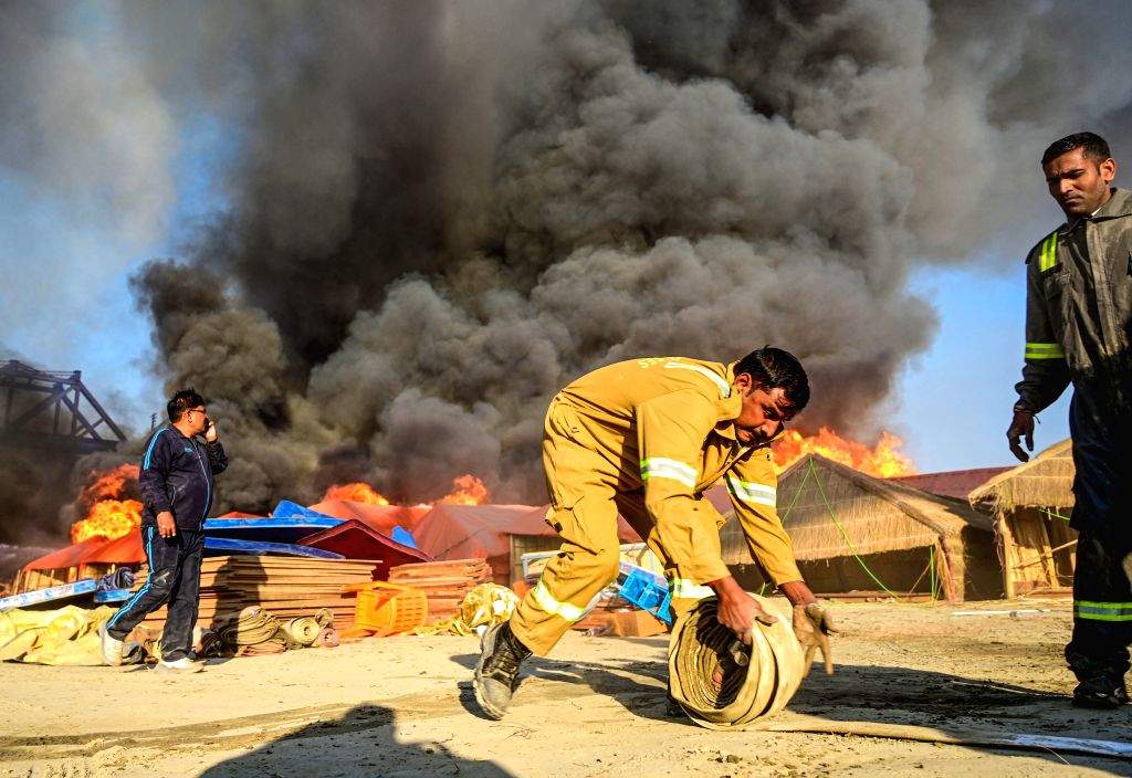 A firefighter prepares to extinguish a fire that broke out at a camp ...