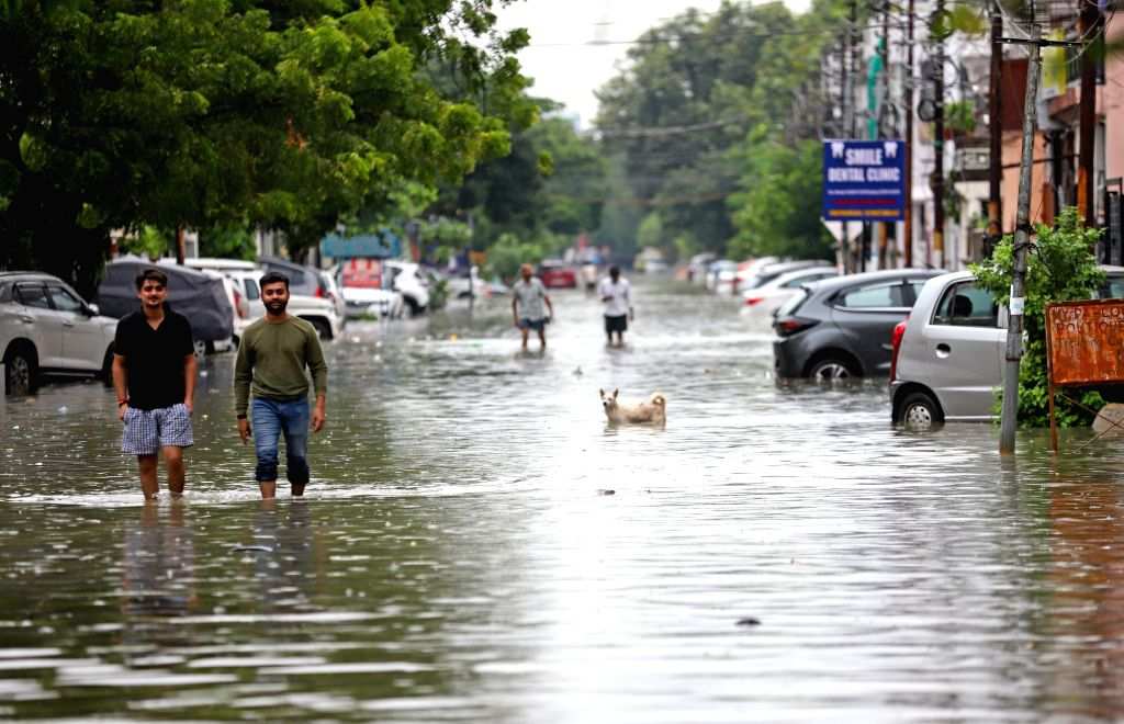 A man wades through a waterlogged road while after heavy rain