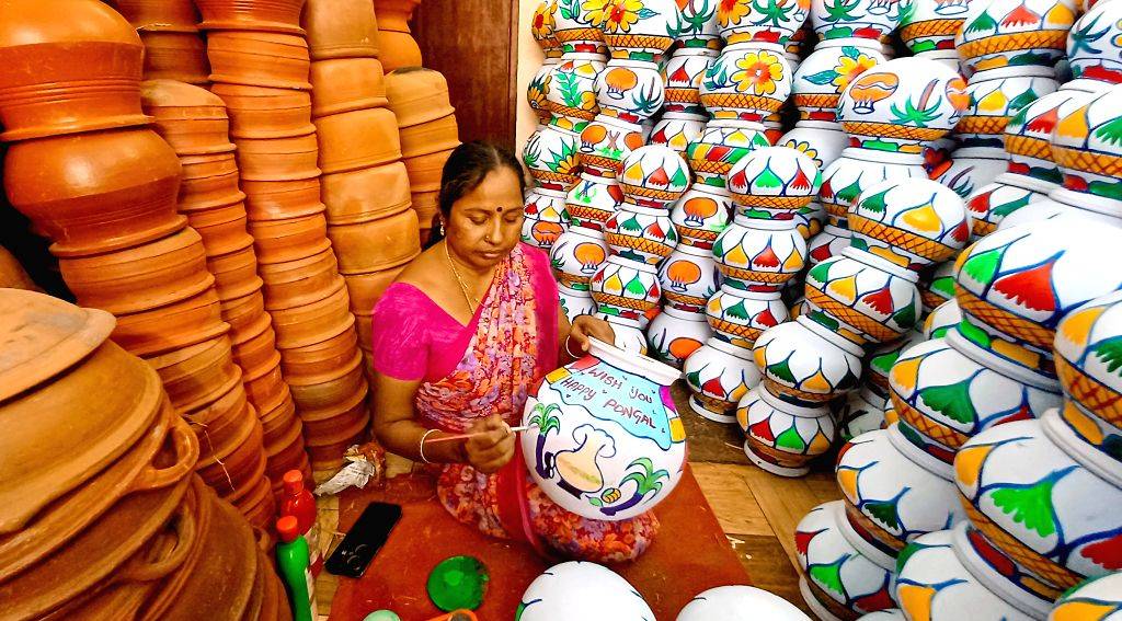 A woman decorates earthenware pots with vibrant designs