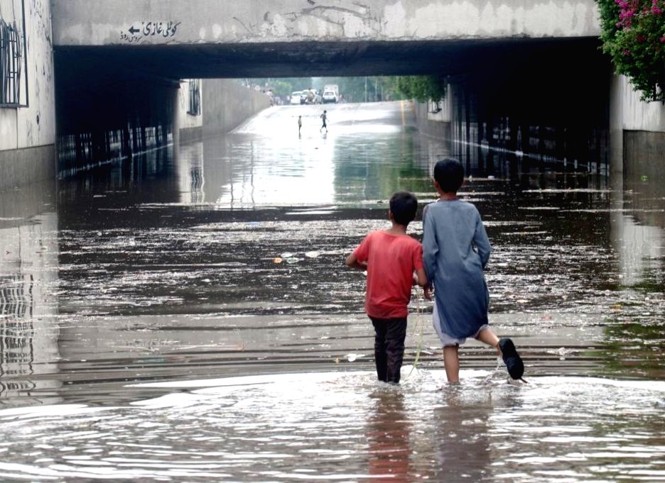 Children wade through flood water after heavy monsoon rains