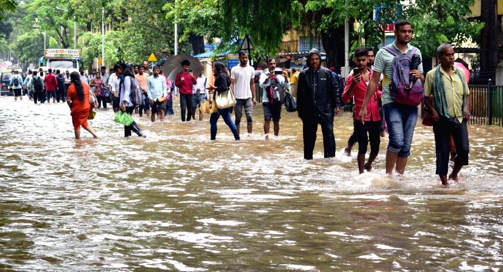 Commuters wade through a waterlogged street after heavy rainfall.