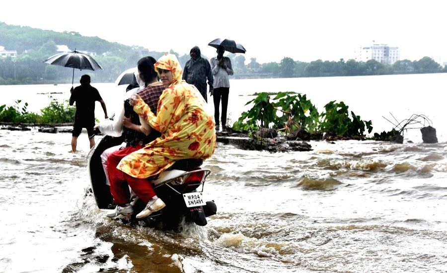 Commuters wade through a waterlogged street after heavy monsoon rains