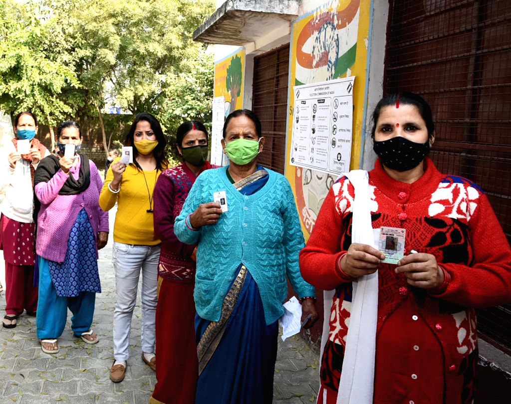 Female voters stand in a queue to cast their vote at a polling booth