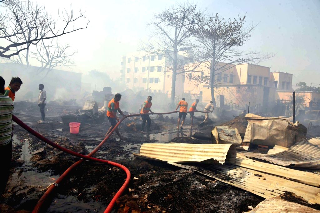Firefighters douse the fire after it broke out in a slum area