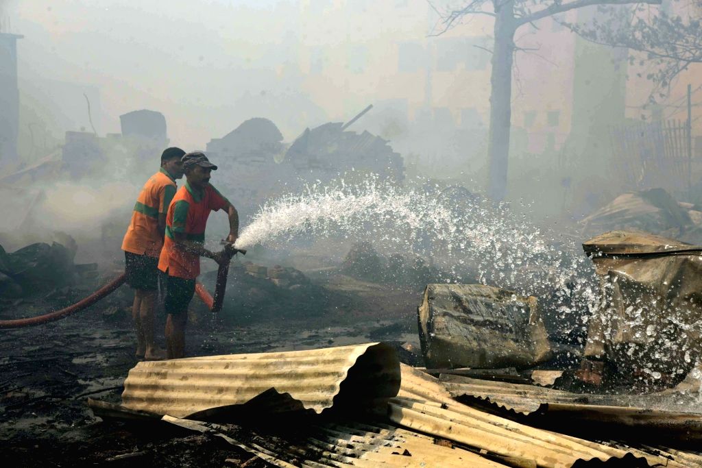 Firefighters douse the fire after it broke out in a slum area