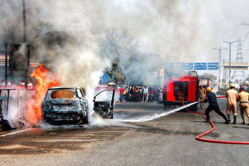 Firefighters try to douse the fire after it caught in a car