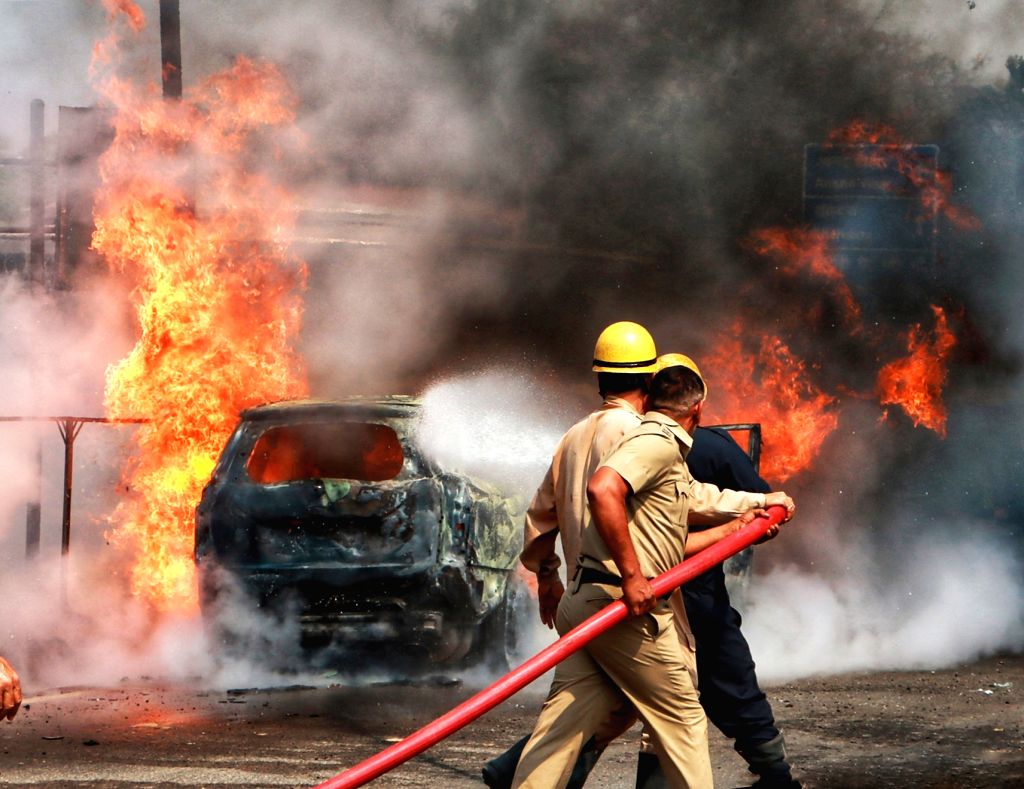 Firefighters try to douse the fire after it caught in a car
