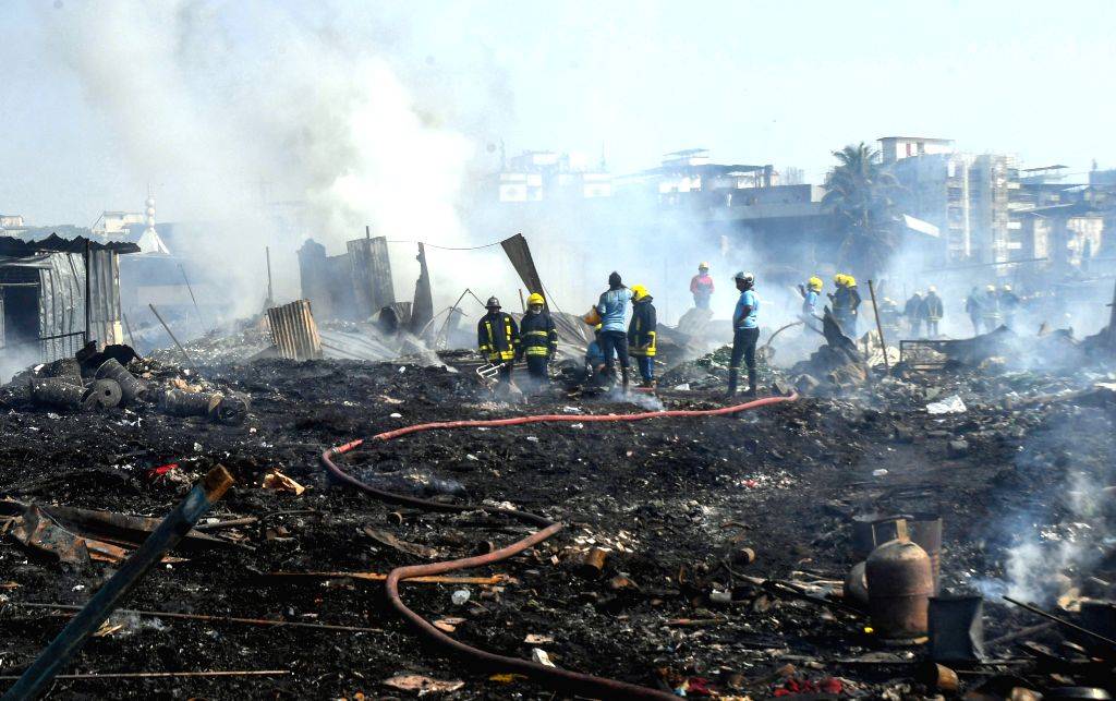 Firefighters trying to douse fire after a fire broke out in a slum