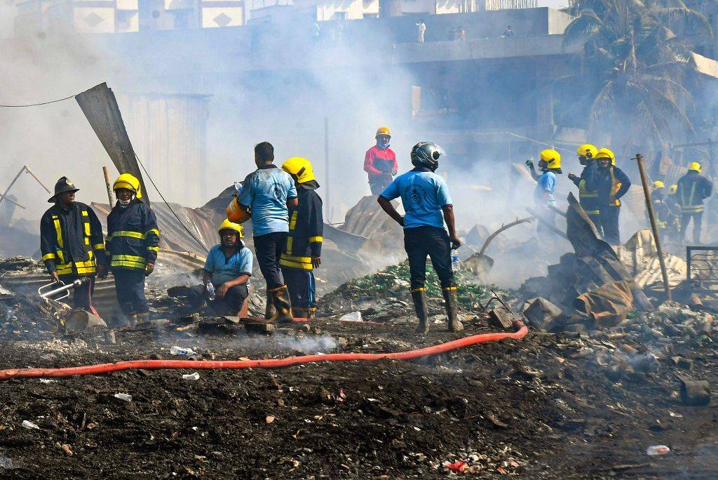 Firefighters trying to douse fire after a fire broke out in a slum