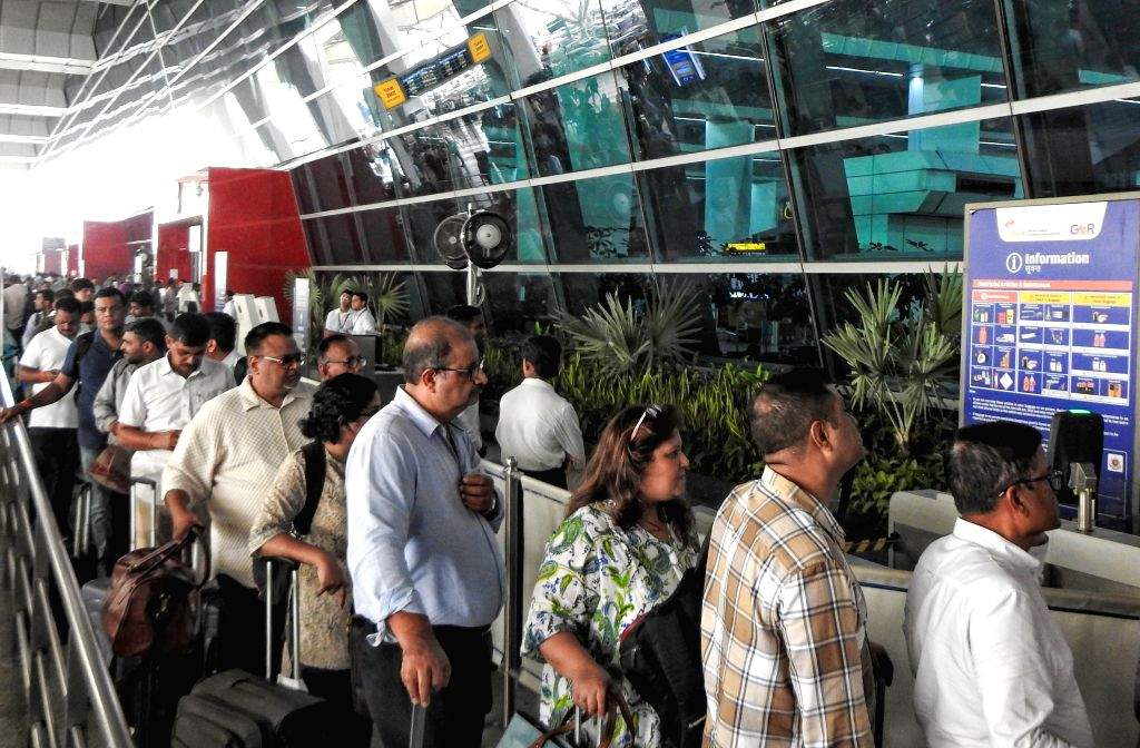 Passengers stand in a queue as they wait due to delays in airline ...