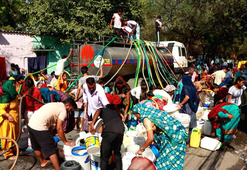 People collect drinking water from a tanker on a hot summer day, at ...