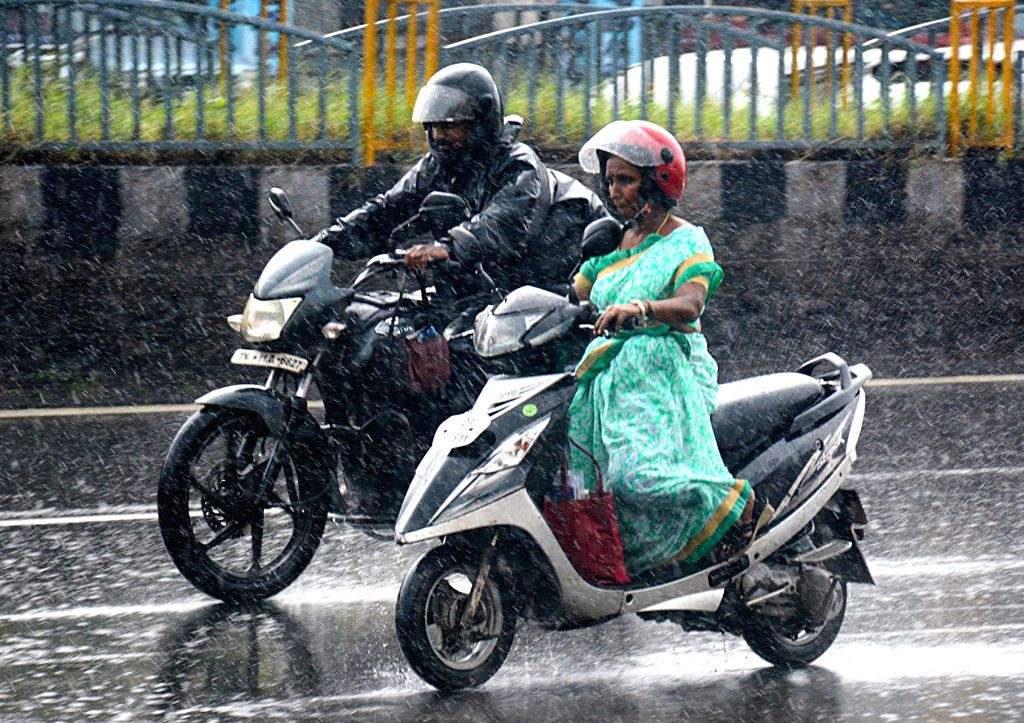 People ride their two-wheelers amid heavy rainfall