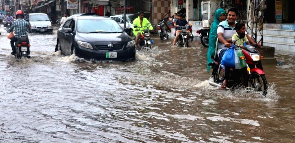 People ride through flood water after heavy monsoon rains in Lahore