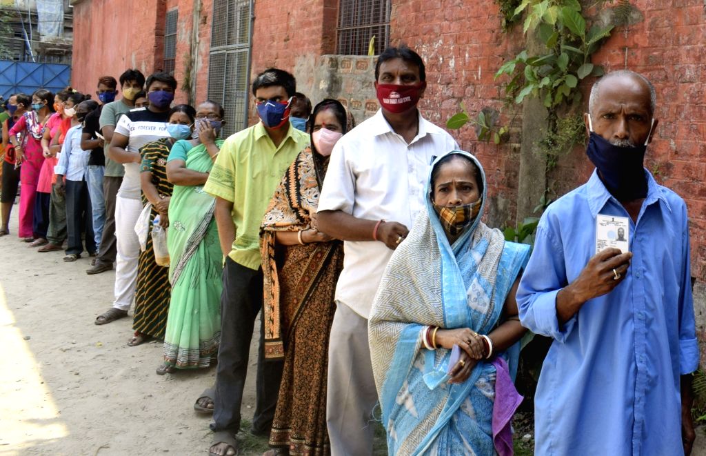People stand in a queue at a polling station to cast their vote at ...