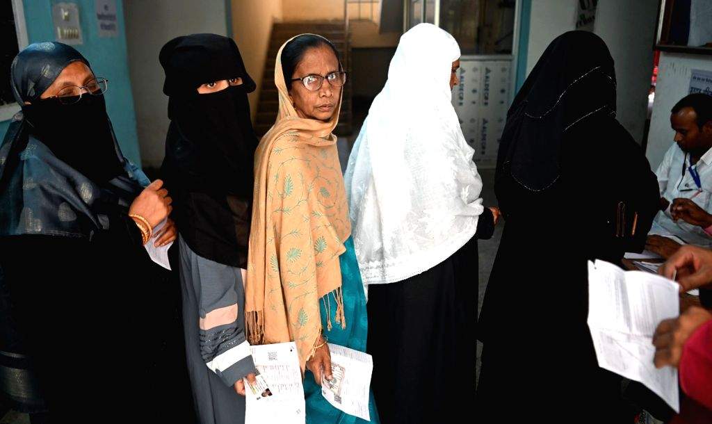 People stand in a queue to cast their votes at a polling booth during ...