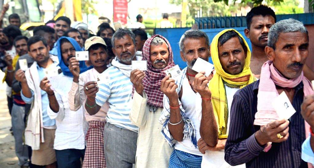 People stand in a queue to cast their votes at a polling booth during ...