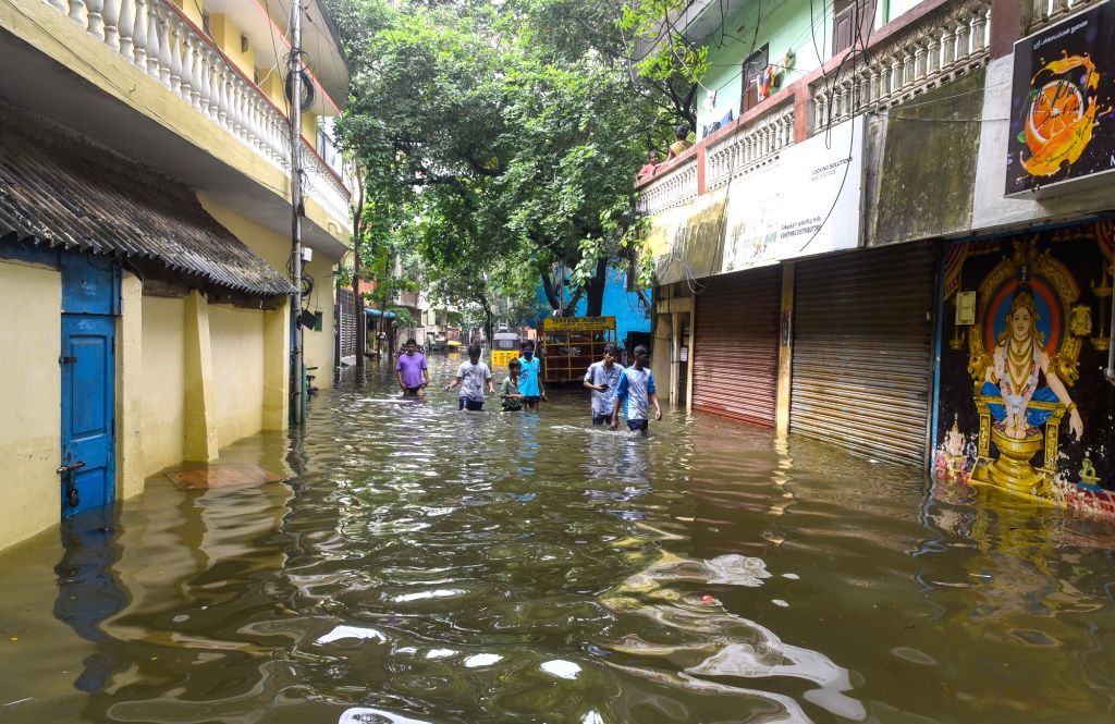 People wade past floodwaters on the outskirts of Chennai following ...