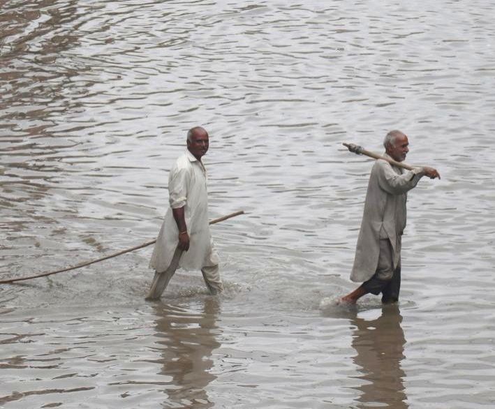 People wade through flood water after heavy monsoon rains in Lahore