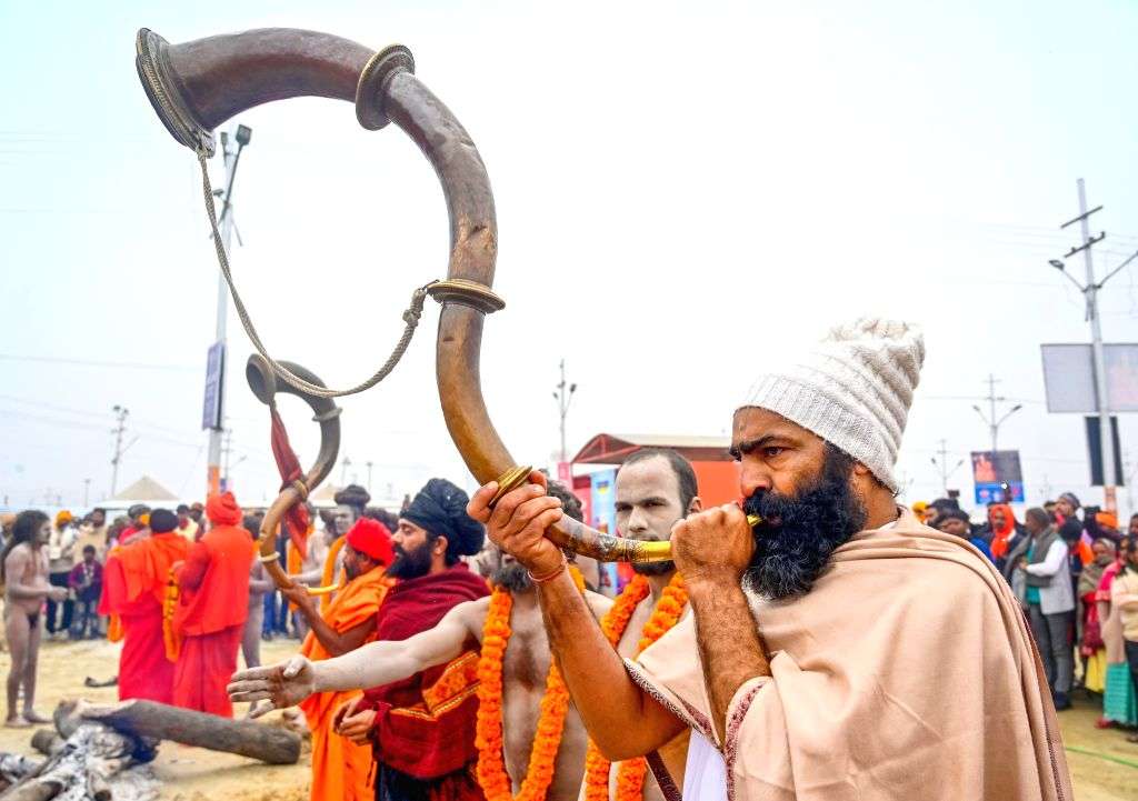 Sadhus blow traditional horns during a ritual at the Triveni Sangam