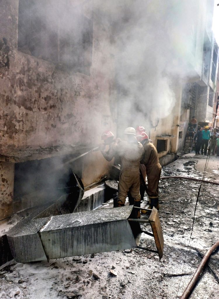 New Delhi : Smoke billows as firefighters try to douse a fire at a showroom