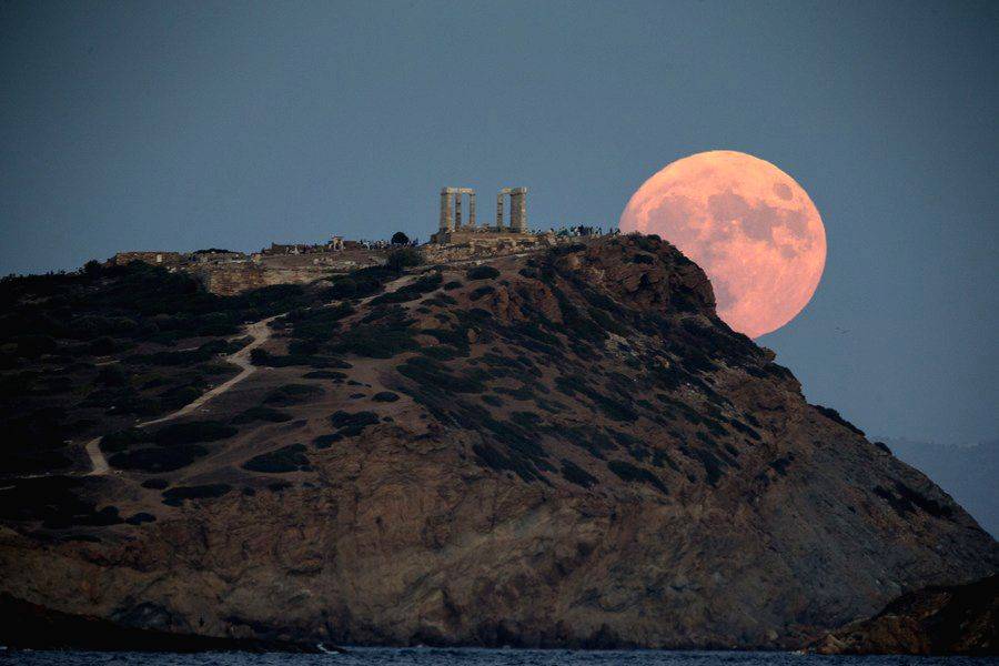 A full moon rises over the Temple of Poseidon at Cape Sounion