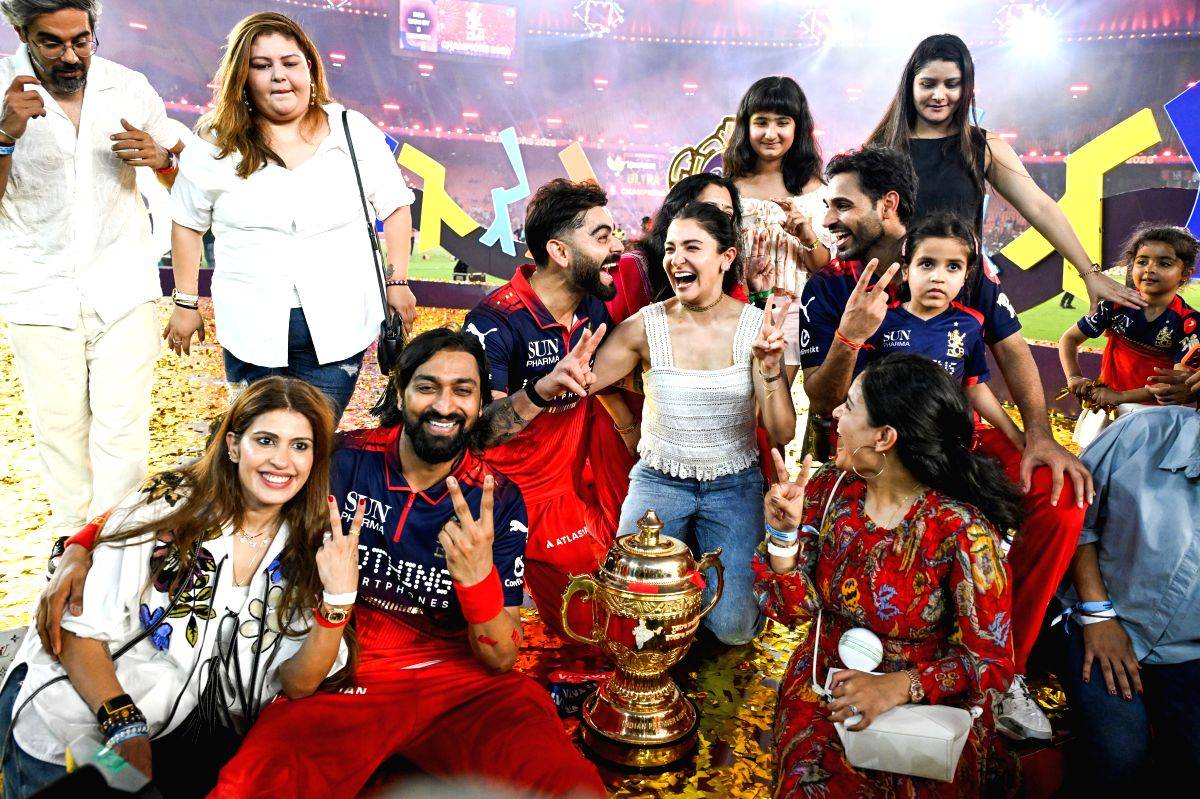 Royal Challengers Bengaluru's Virat Kohli, along with his wife Anushka Sharma, and players Krunal Pandya and Bhuvneshwar Kumar along with their families, celebrate with the winner's trophy