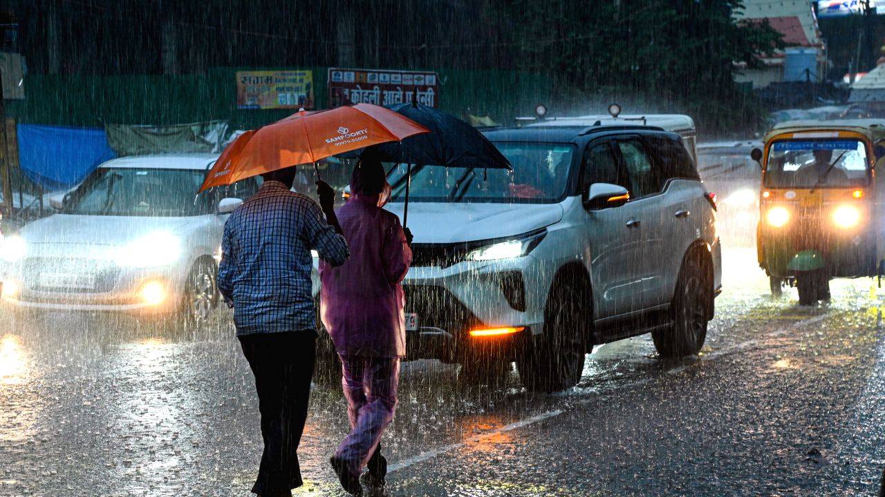 Commuters cross a road amid heavy rainfall in Gorakhpur 