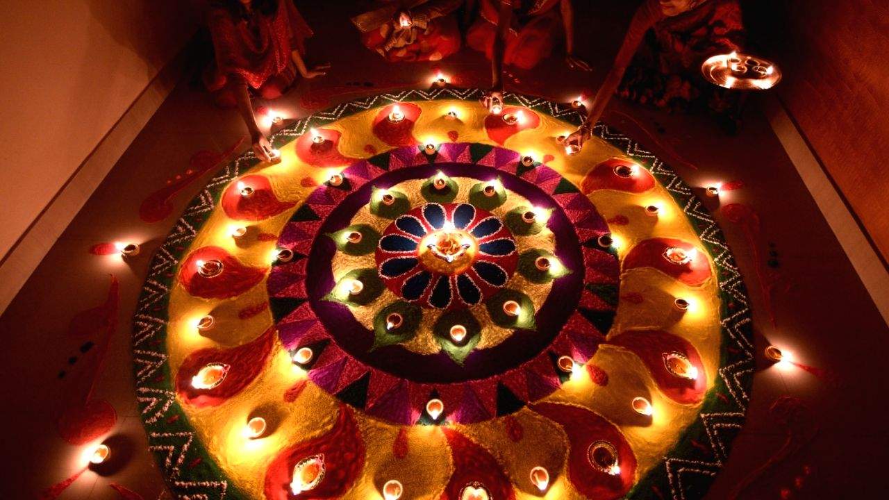 Women light earthen lamps on Diwali